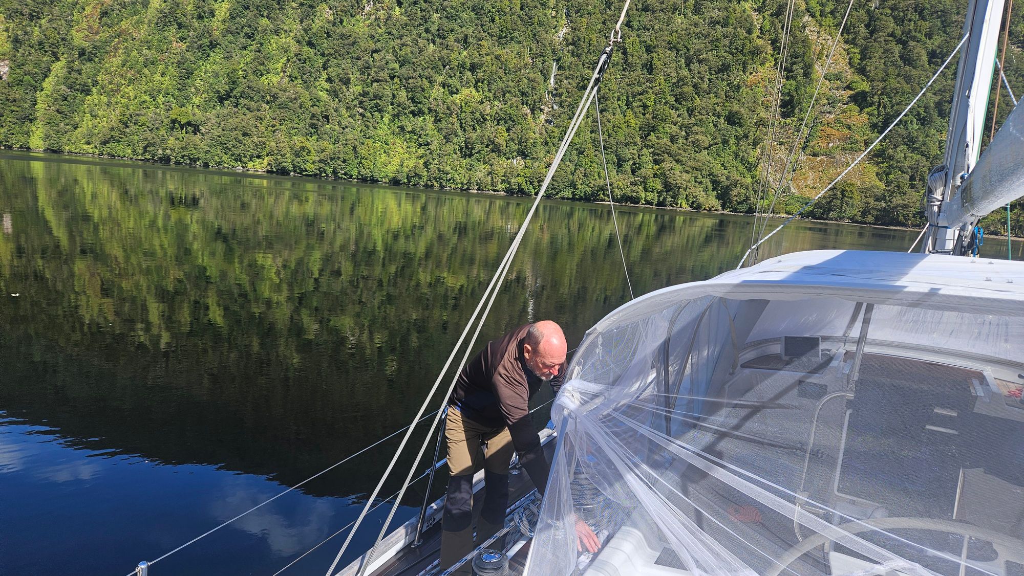 Bruce deploying a bug net over the cockpit of Matariki III at anchor in Dusky Sound — the sandfly defence system