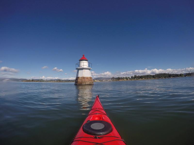 Kayak rouge et un phare dans le fjord