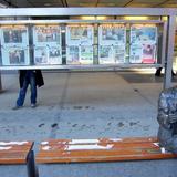 Photo d'une statue d'un homme lisant un journal, devant des unes du journal VG