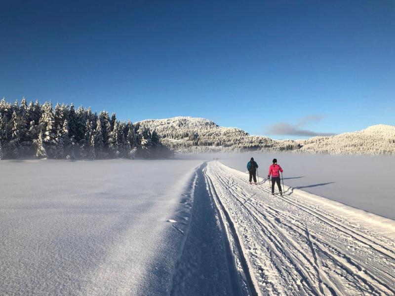 Deux personnes faisant du ski de fond classique sur un lac gelé