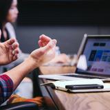Photo d'une personne assise à une table devant son ordinateur et parlant aux autres