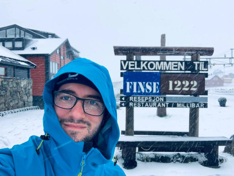 Thomas sous la neige devant le panneau de la station de train de Finse