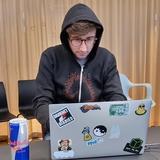 Portrait de Camille devant son ordinateur avec son pull à capuche de « hacker »