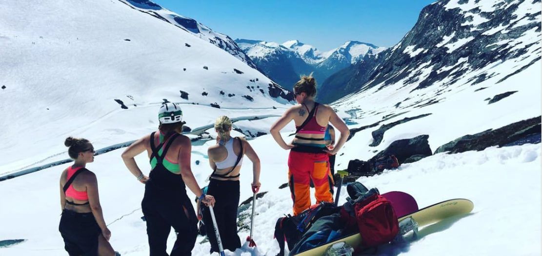 4 personnes en tenues d'été mais à ski dans une montagne enneigée