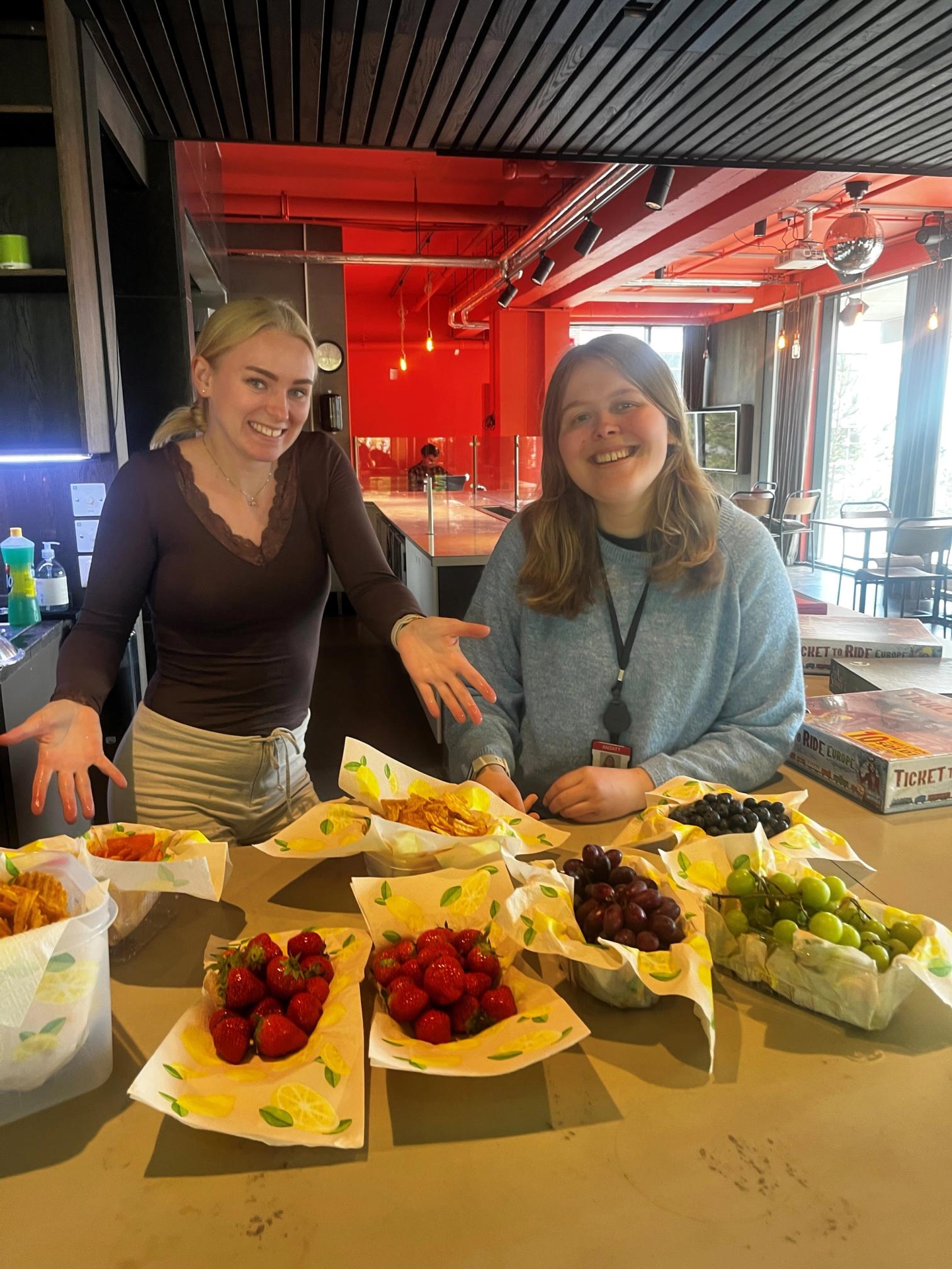 to blide jenter som poserer foran et bord med masse frukt