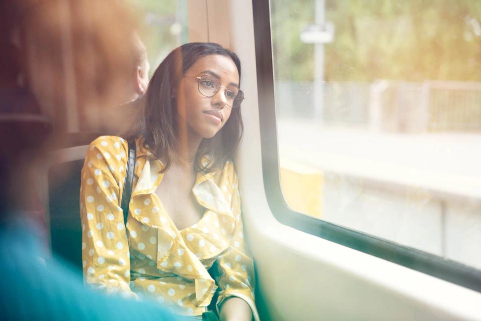 Girl sitting and looking out the window on the subway