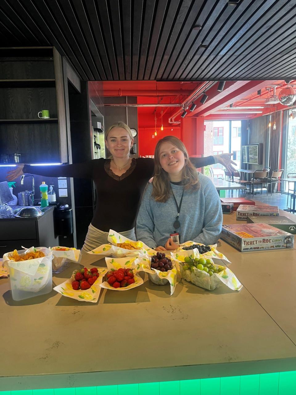 To jenter med fat foran seg med masse frukt.