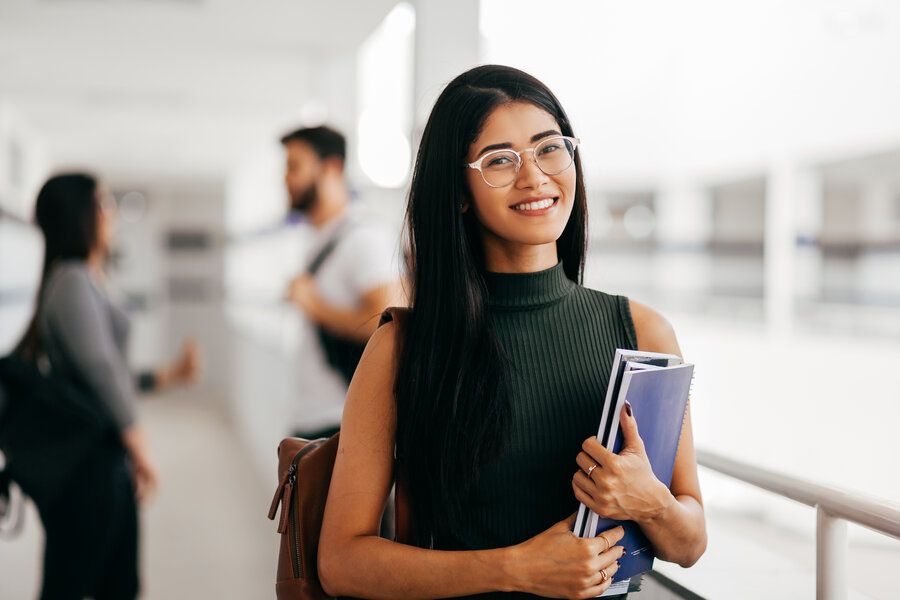 Female Asian student smiling, carrying notebooks