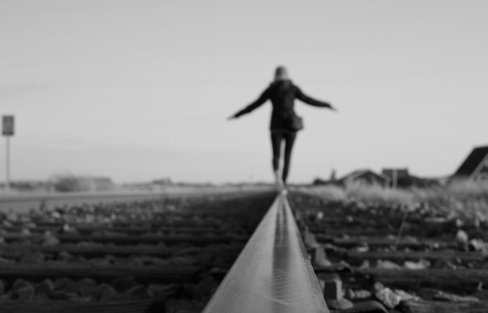 Person balancing on a railroad track with arms outstretched.