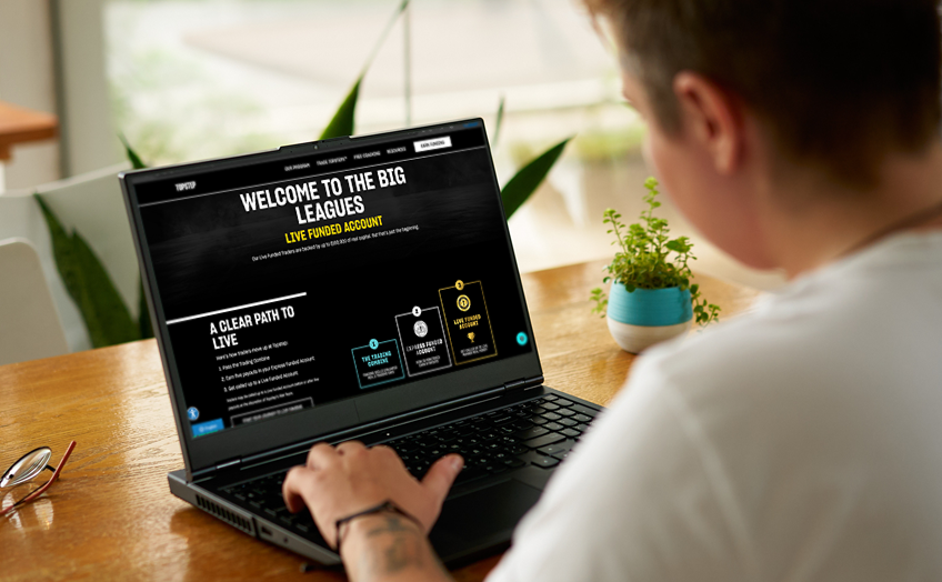 Person using a laptop with a trading platform at a desk.