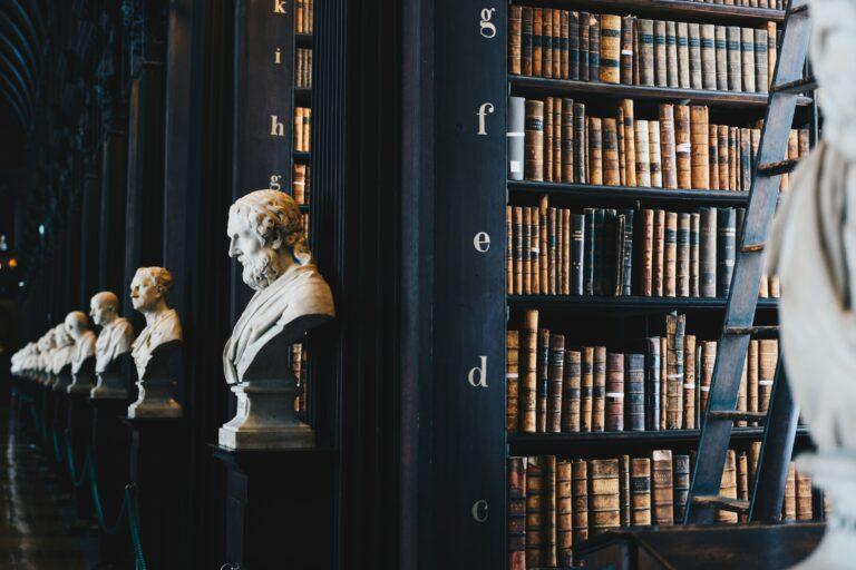 Library shelves with classical busts and rows of old books.