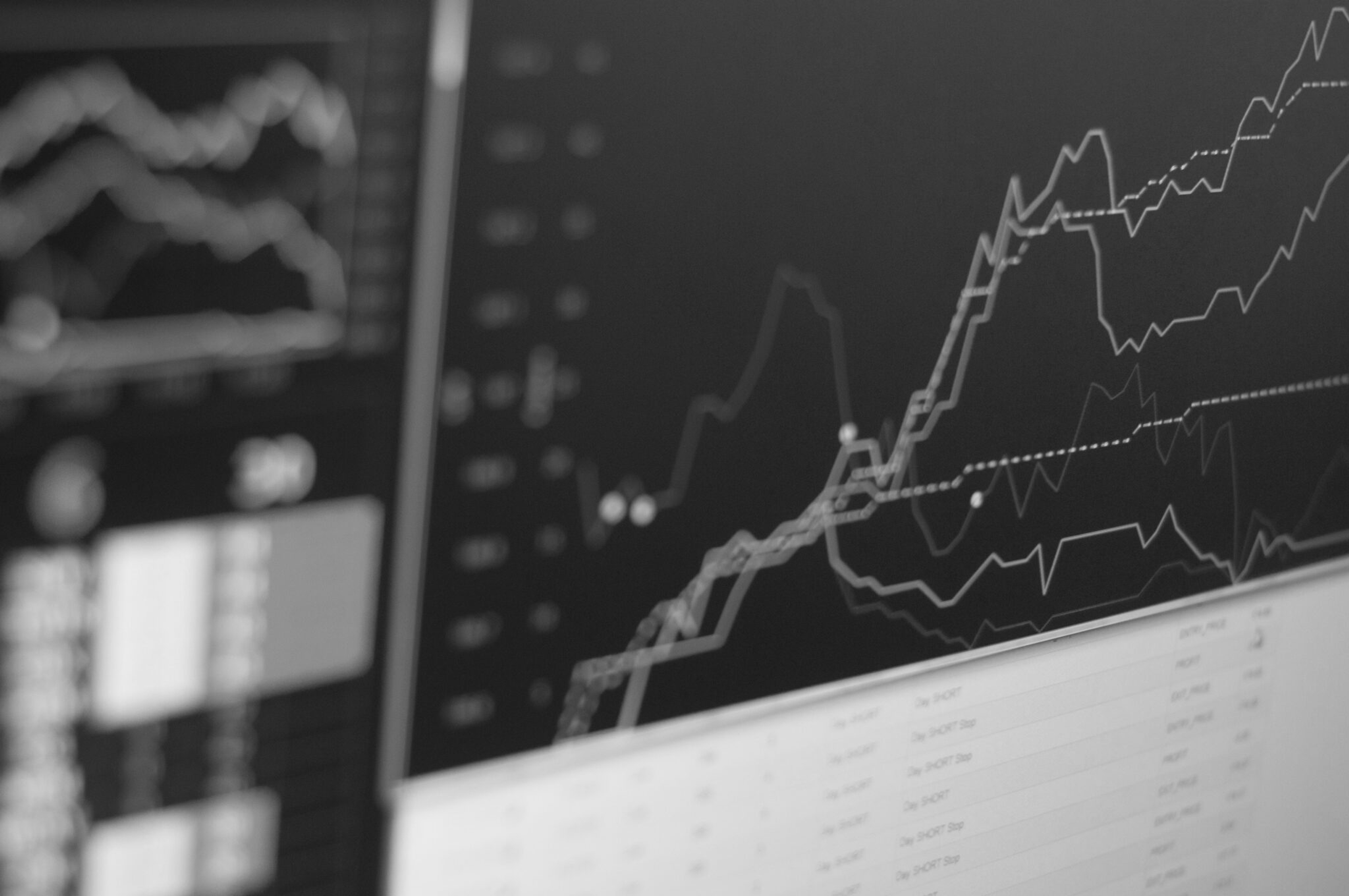 Black-and-white screens showing financial charts and upward market data.