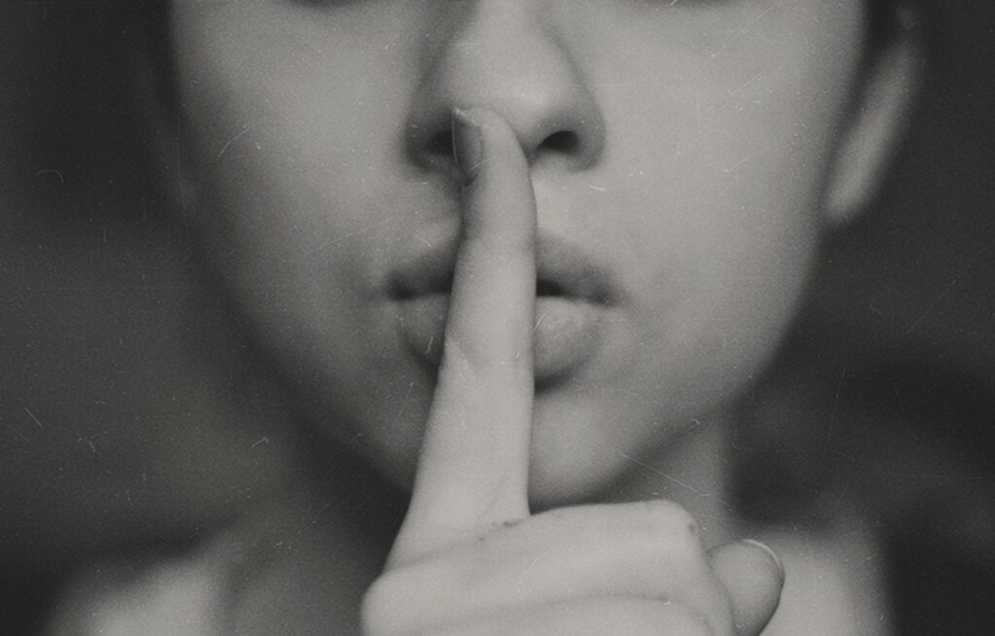Person holding a finger to their lips in a gesture for silence.