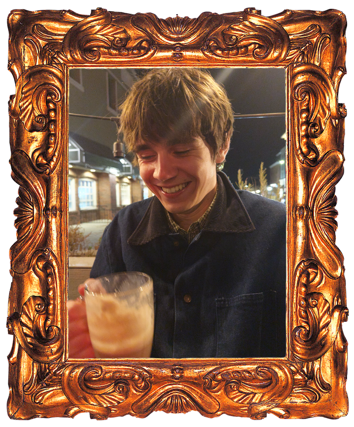 Charlie Andrade laughing over an iced chai on a patio at night