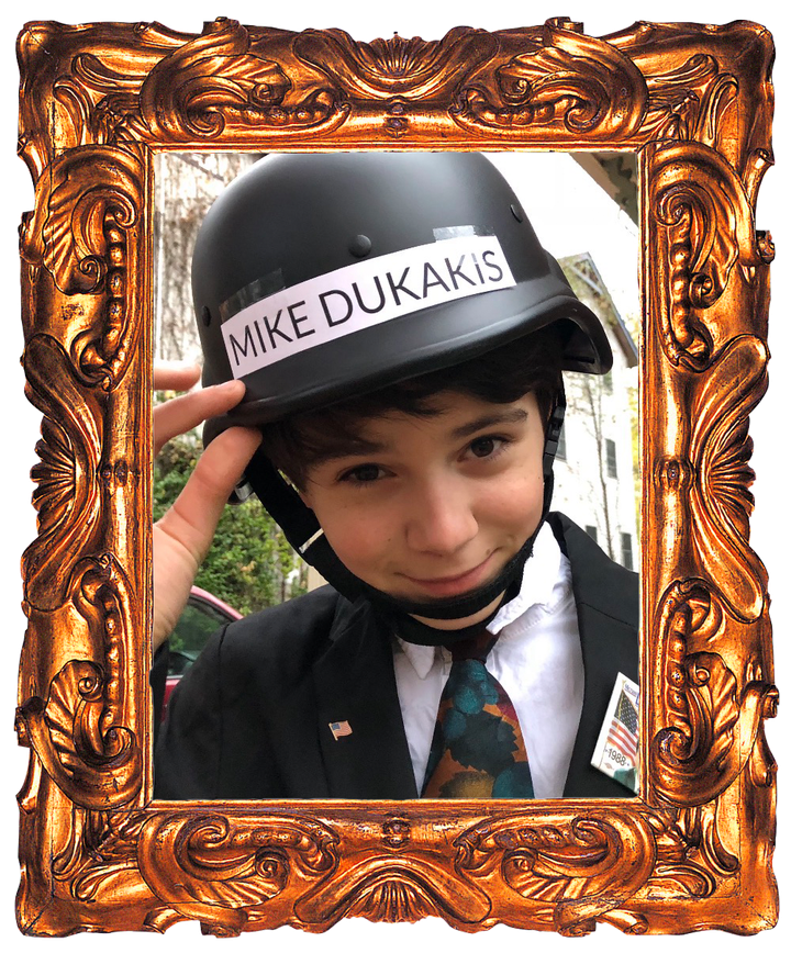 A young Charlie Andrade dressed as Michael Dukakis, in a suit and a tank helmet labelled MIKE DUKAKIS