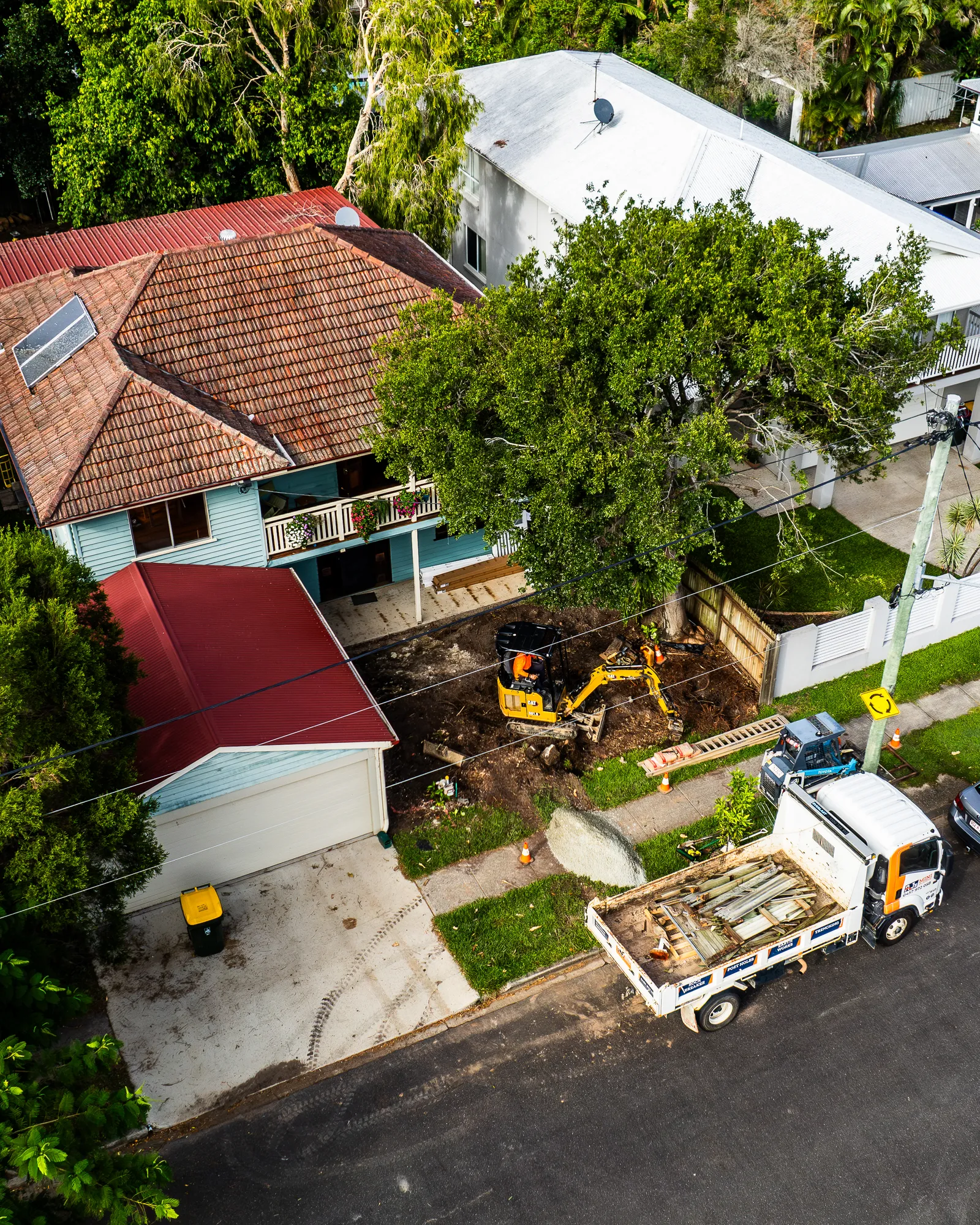 A drone shot of landscapers working in the front yard of a home.