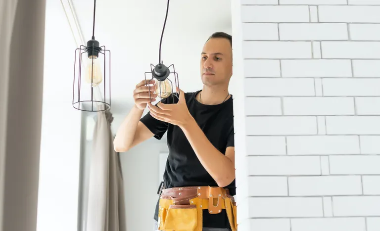 Electrician installing a light fixture in a home