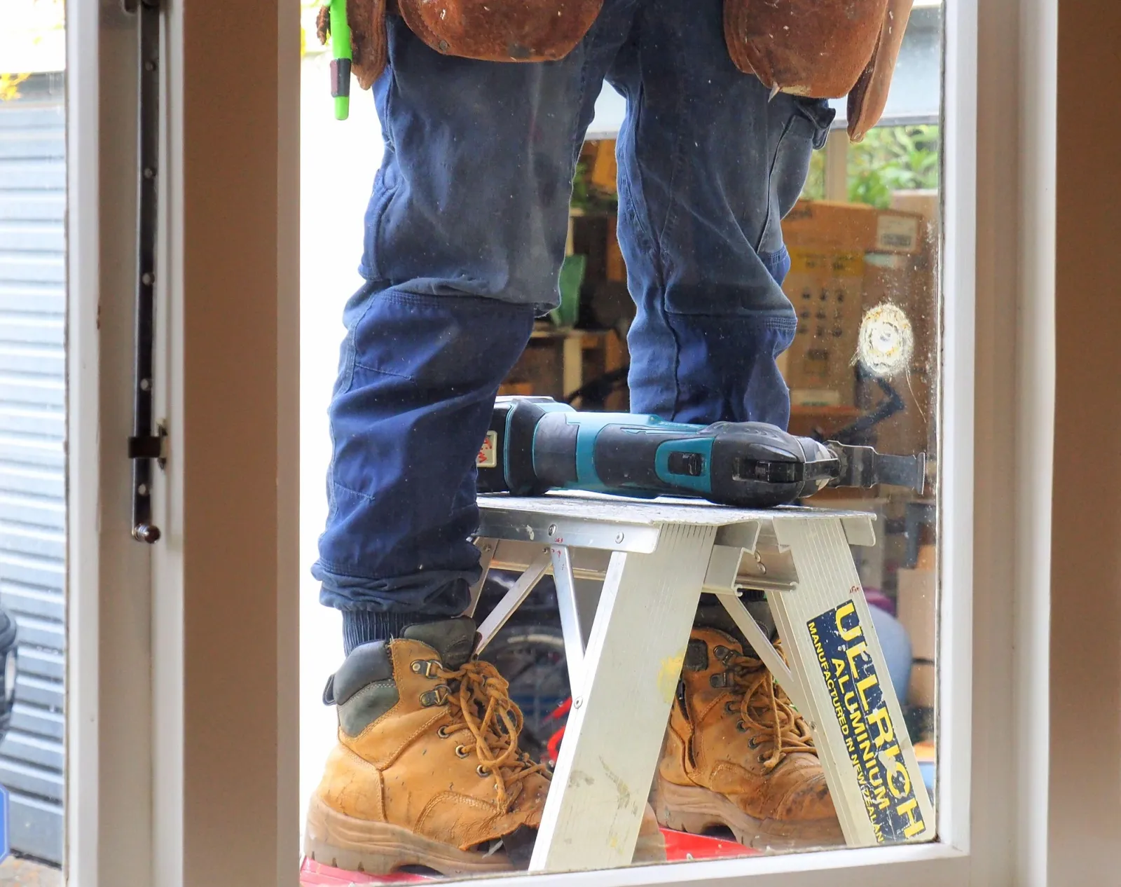 Handyman on a stepladder using an oscillating saw