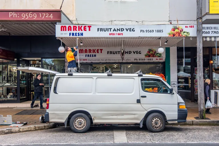 An electrician installing a light at a commercial storefront