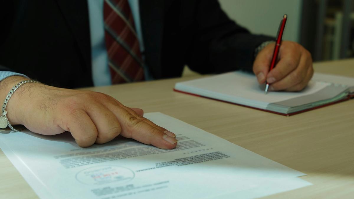 Applicant completing paperwork and scanning documents for a temporary real estate license application.
