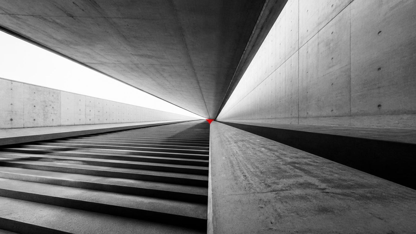 Converging concrete lines and steps meeting at a single vanishing point, with a small accent mark at the convergence.