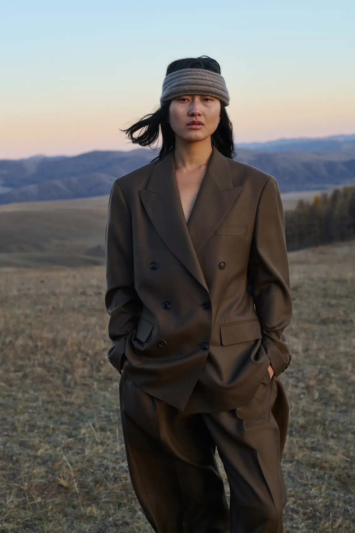 A woman in cashmere brown suit with a beige cashmere headband in scenic nature
