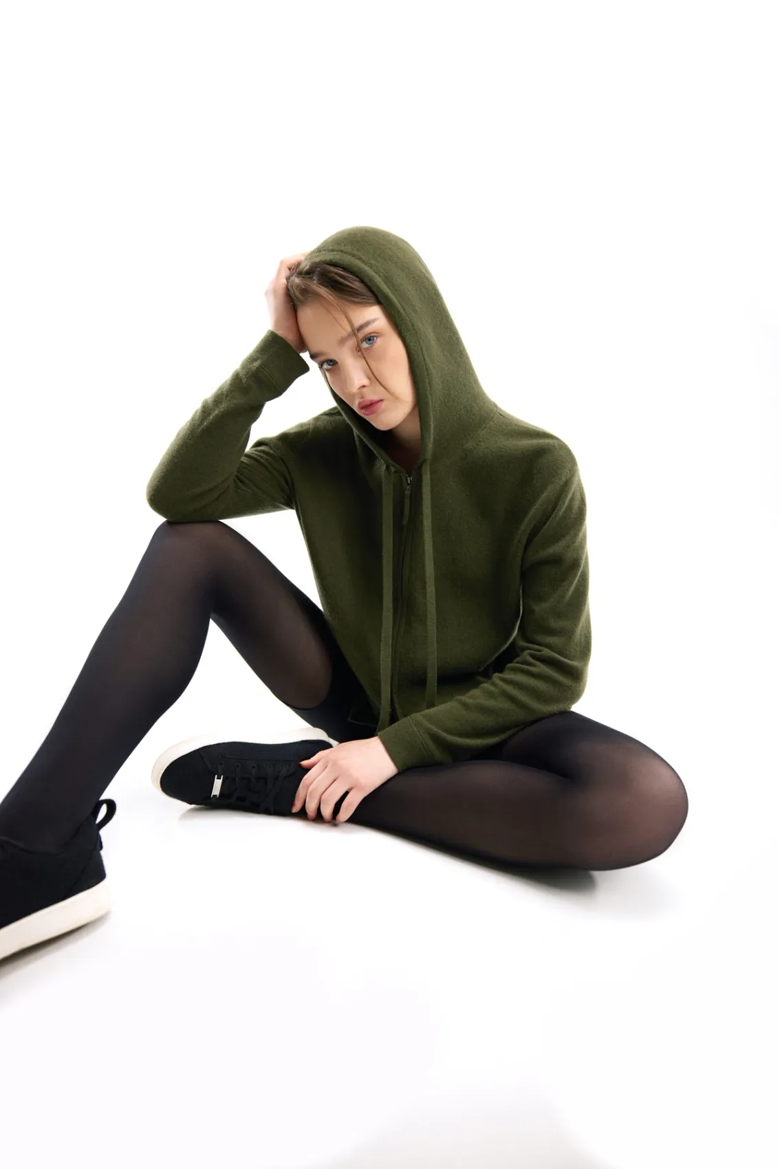 model wearing an olive green cashmere hoodie with cashmere sneakers