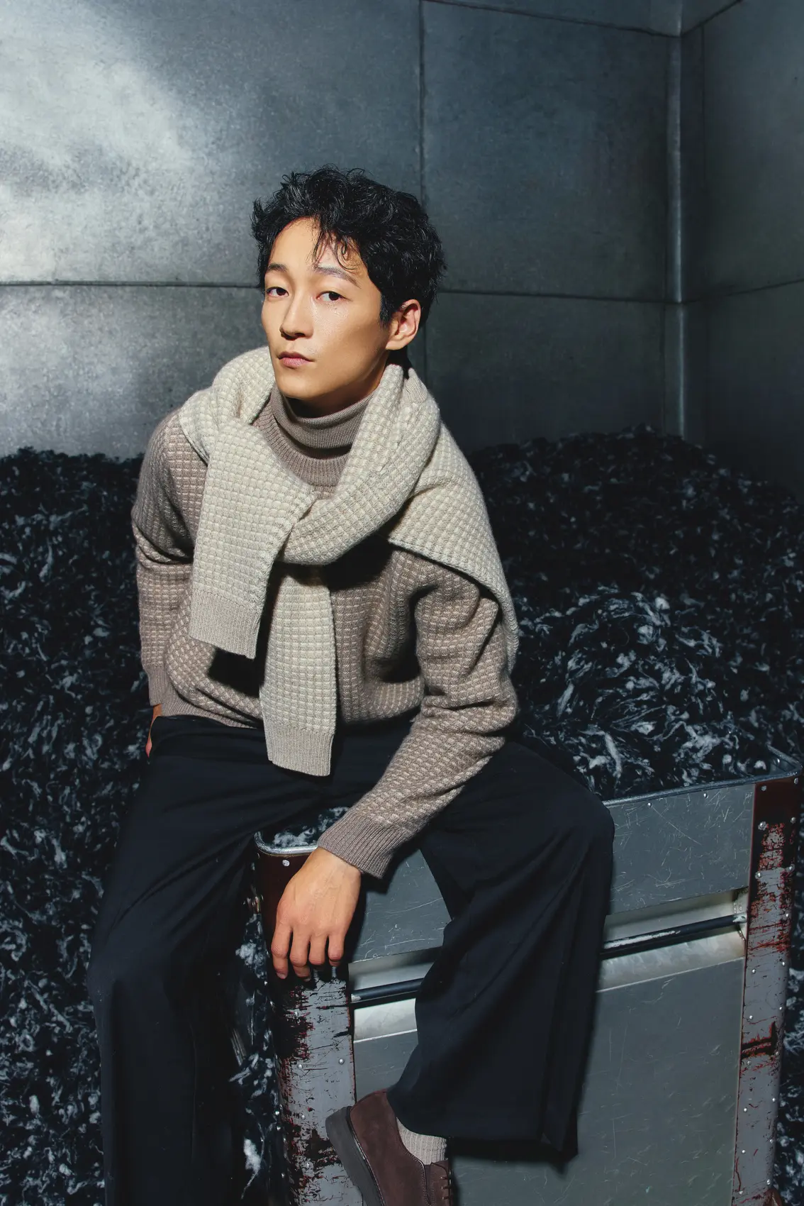 A man wearing cashmere sweater and sitting on a raw cashmere collector.