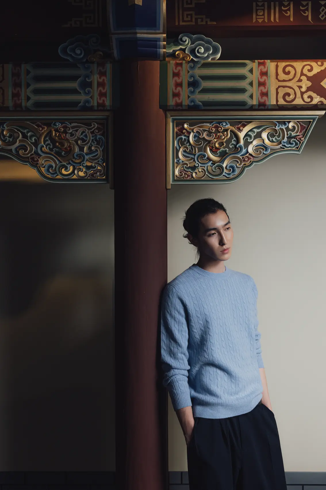 Man in a light blue cashmere sweater leaning against a pillar with ornate details. | GOBI Cashmere