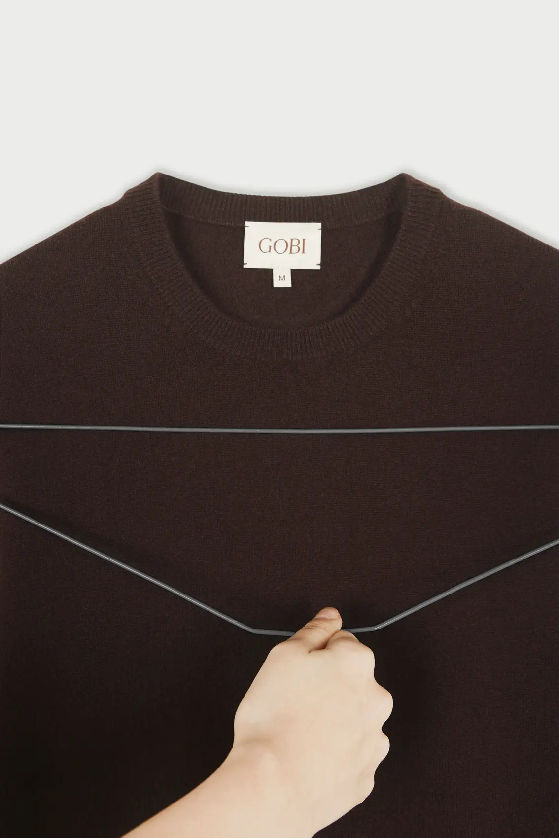 Using metal hanger to get rid of static from cashmere jumper | GOBI Cashmere