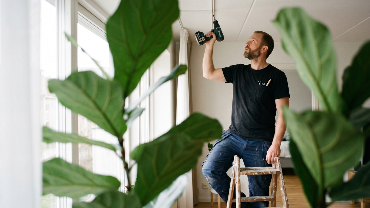 Handyman skruvar upp gardinskena i taket