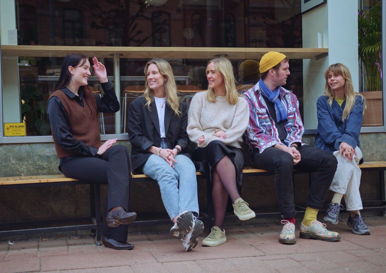 Fem personer sitter på en bänk