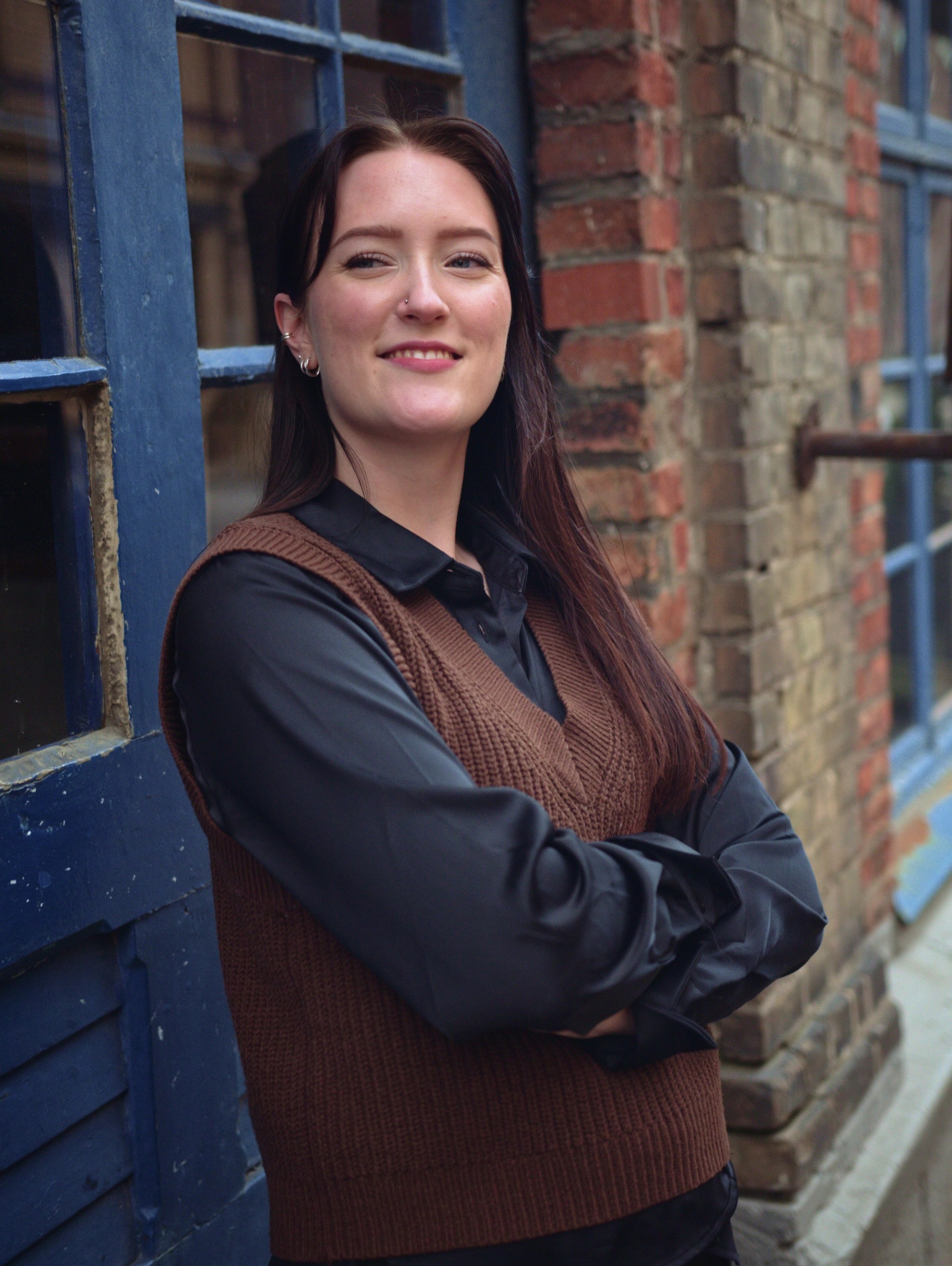 Kvinna som håller armarna i kors som ler och tittar åt vänster