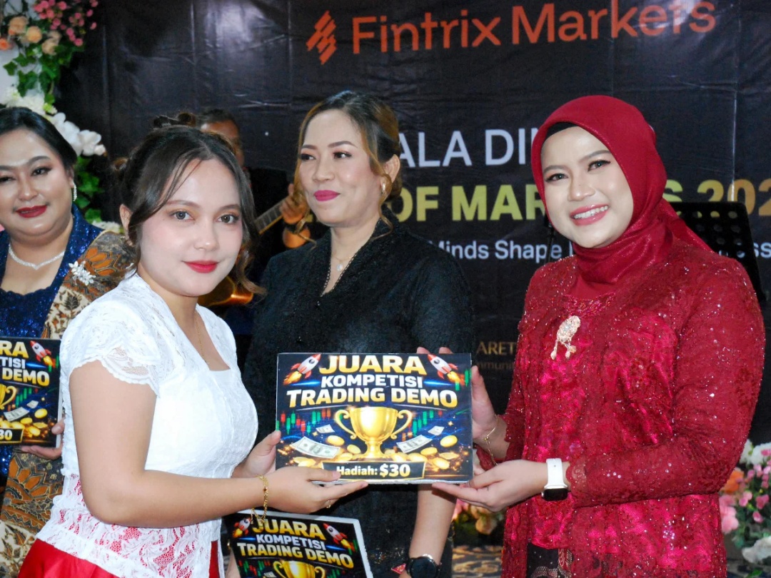 Women hold a demo trading competition prize placard at the Fintrix Markets Kartini event.