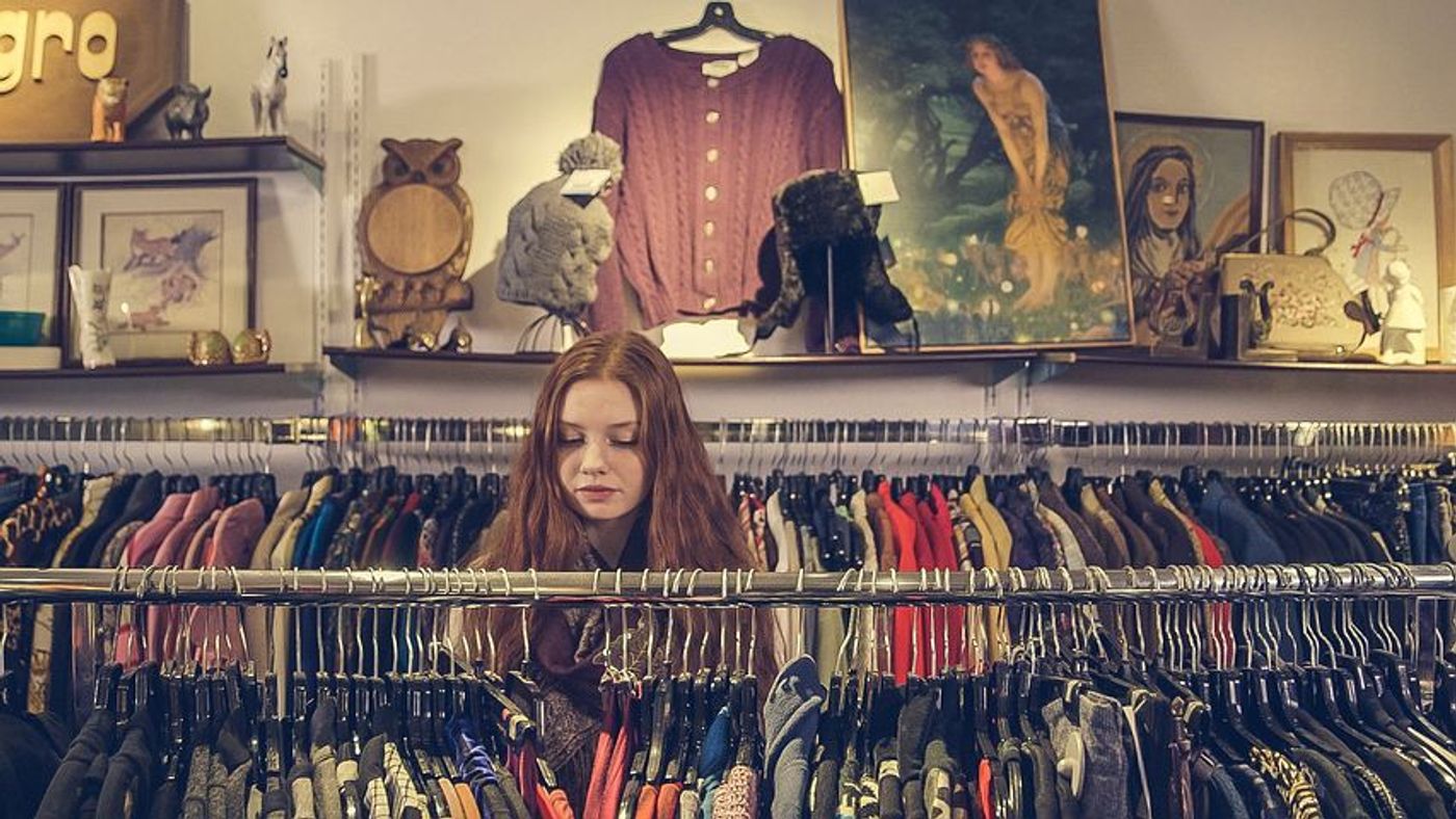 How to sell clothes on Amazon: A woman with long red hair looks at clothes in a clothing store. 
