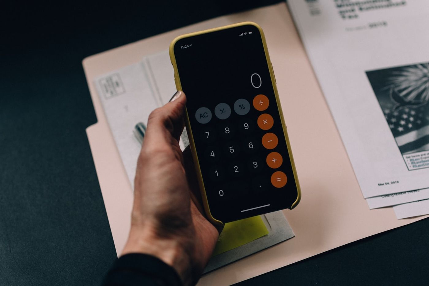 A woman's hand holds an iPhone with the calculator app pulled up.