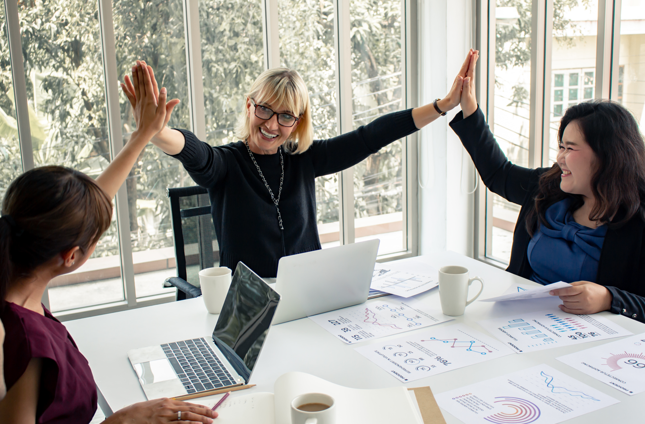 Overly staged stock photo of coworkers high-fiving across a meeting table