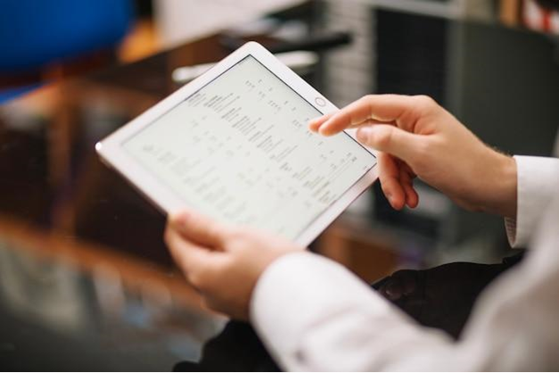 A person working on a tablet using stock/inventory and supply chain check utilising blockchain technology.