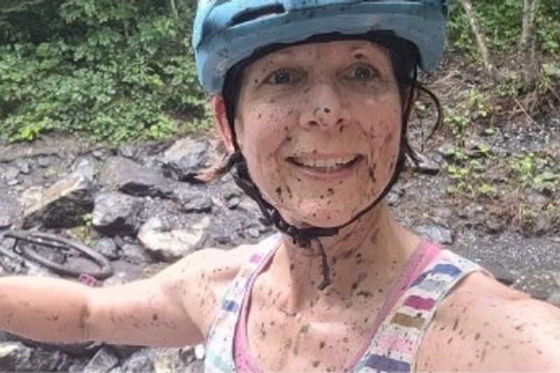 Fiona, smiling and splattered with mud, wearing a cycling helmet
