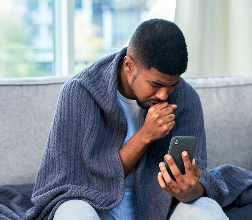 A person coughing into their phone to take a Helfie check