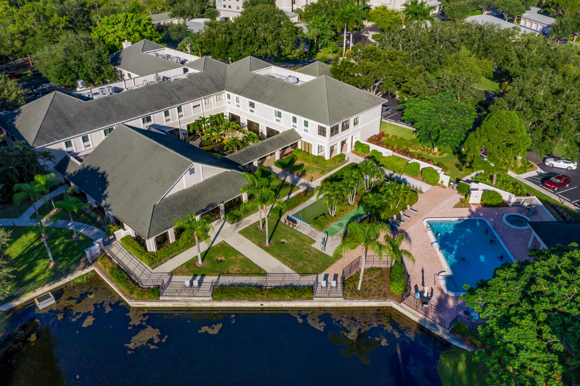 Aerial view of the clubhouse courtyard, pool, and grounds