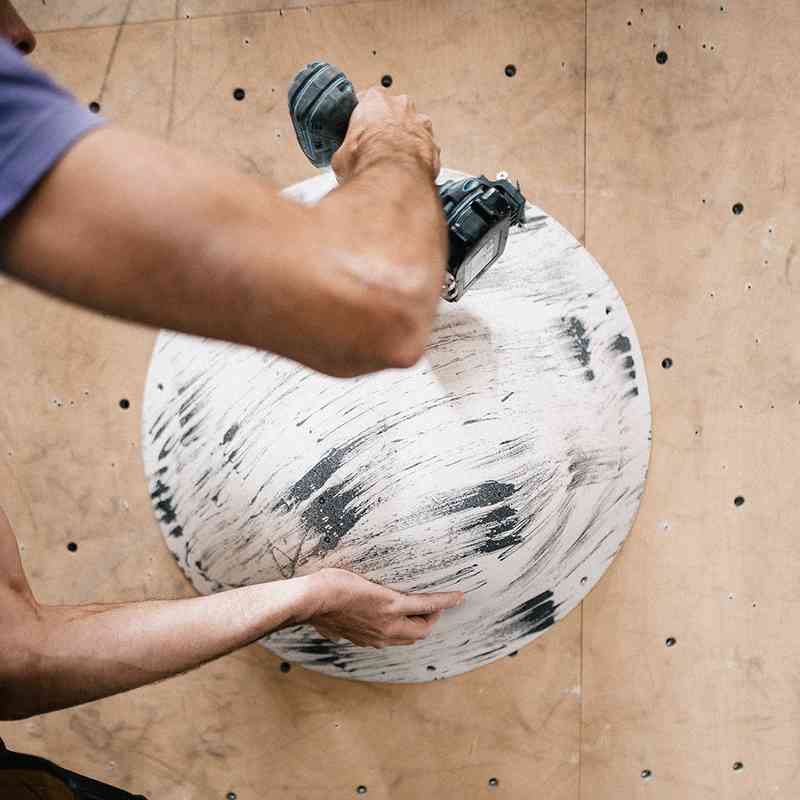 Matthias Woitzuck mounting a climbing volume to the wall with a screwdriver.