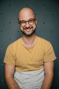 Jan Haiko laughing in front of a climbing wall.