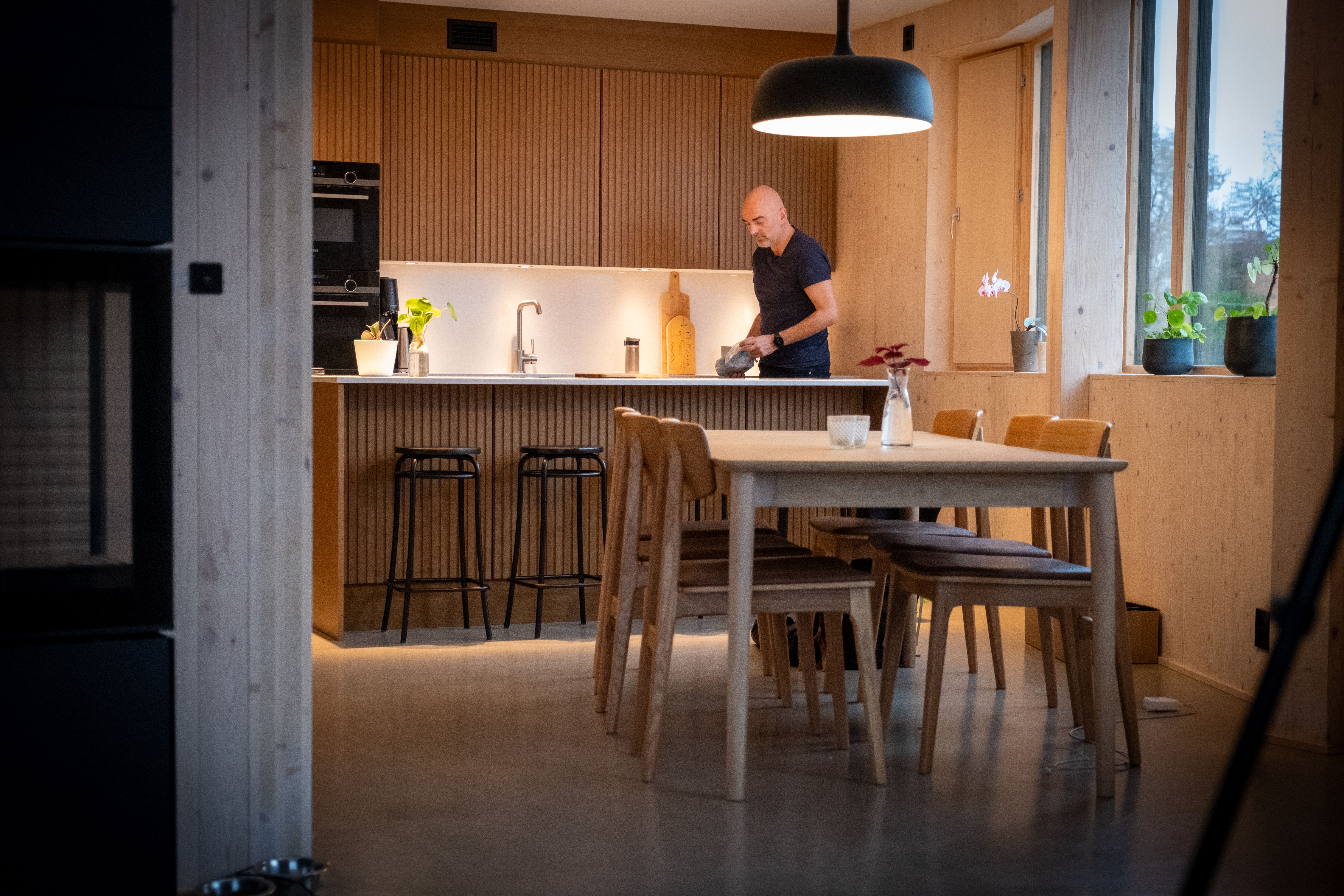 Nikolaos Farmakis står på kjøkkenet i boligen sin, omgitt av treflater og store vinduer