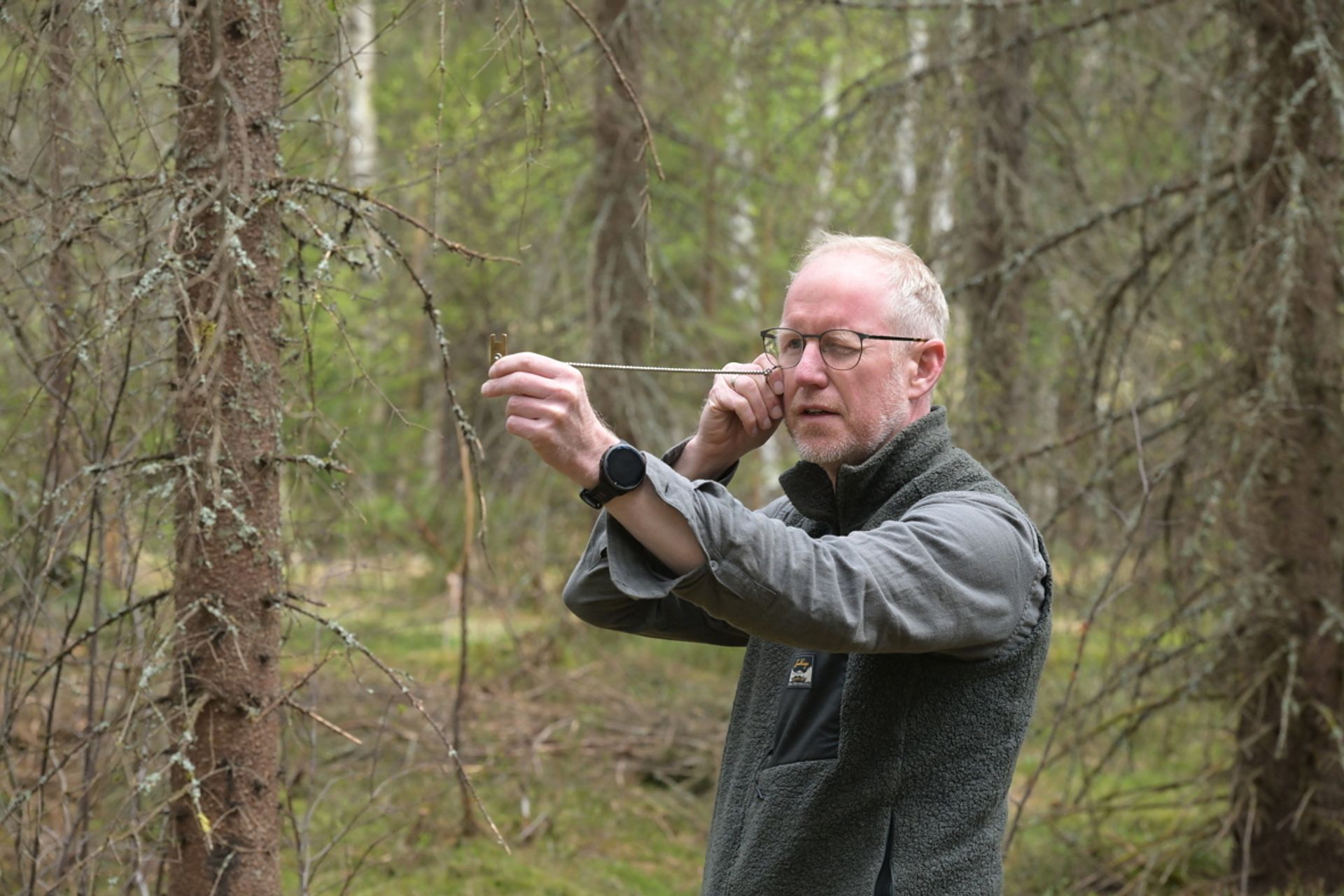 Christer Sandum bruker et relaskop for å sjekke om det trengs tynning.