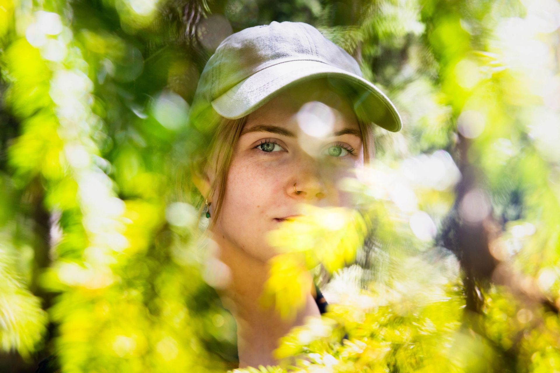 Nærbilde av Elin Johanne mellom grønne grangreiner i skogen.
