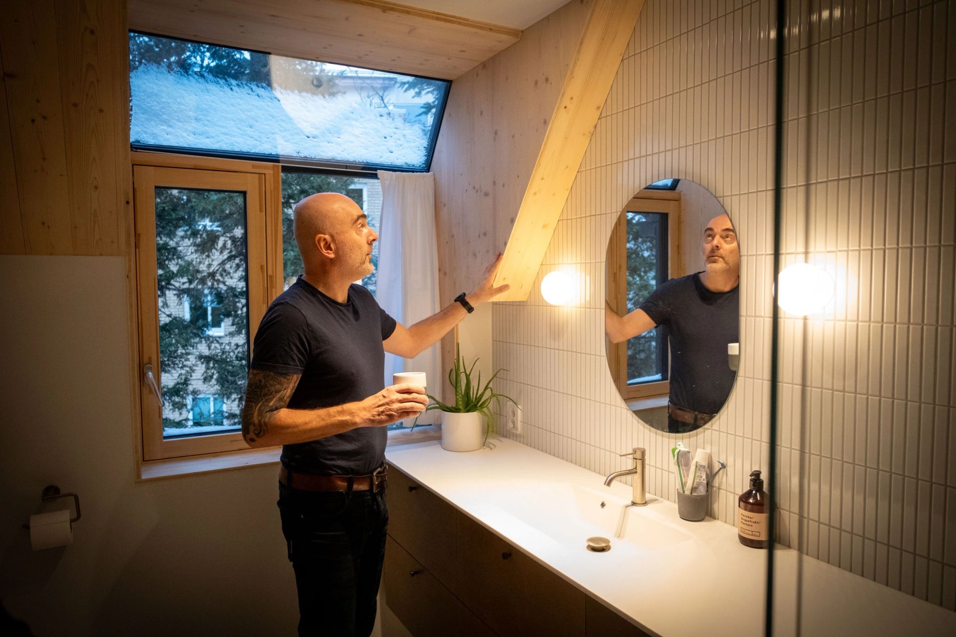 Nikolaos Farmakis viser fram en synlig limtrebjelke på badet, der treverket er en del av interiøret.