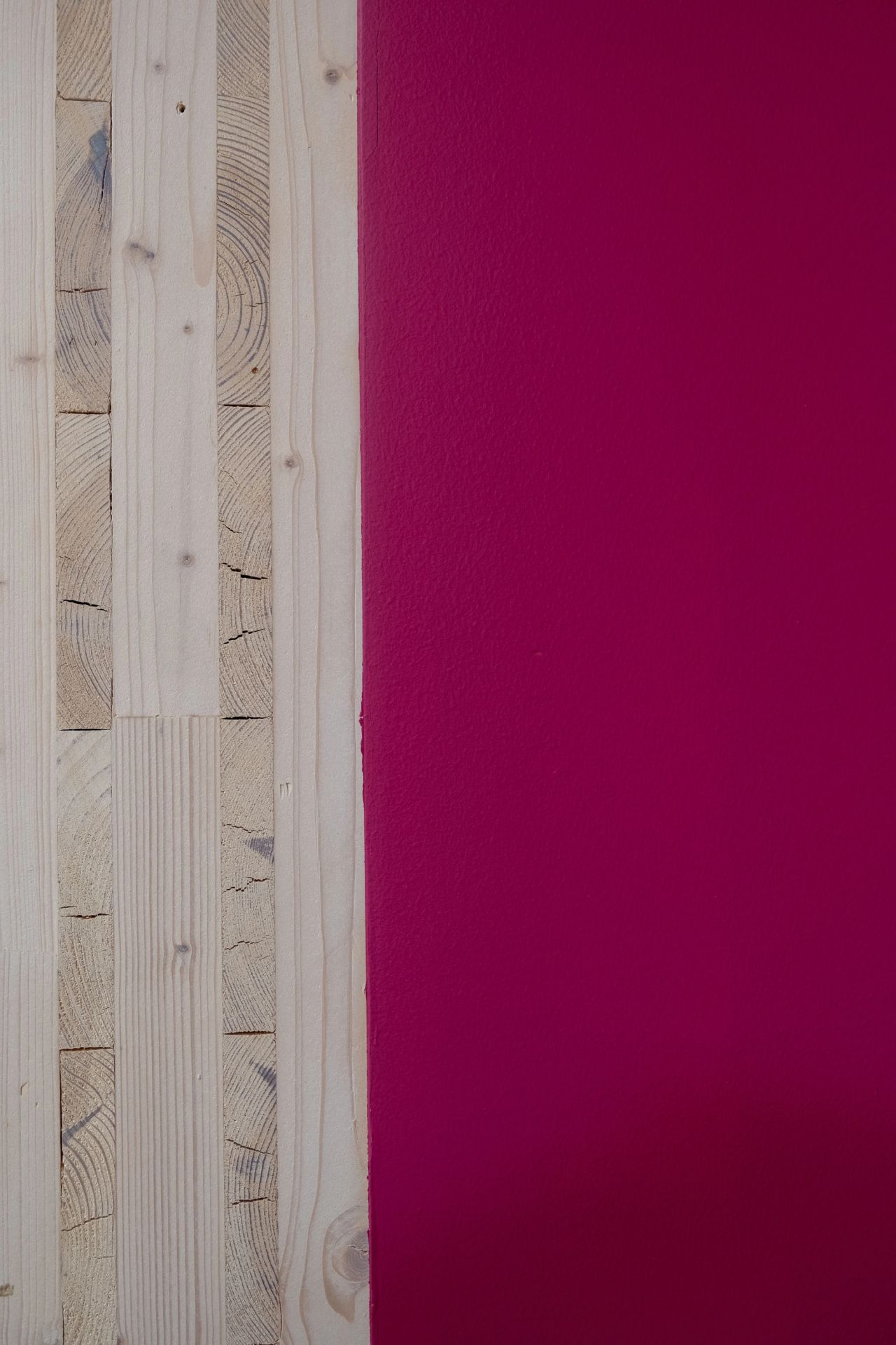 Nærbilde av massivtrevegg ved siden av en sterkt rosa malt vegg.