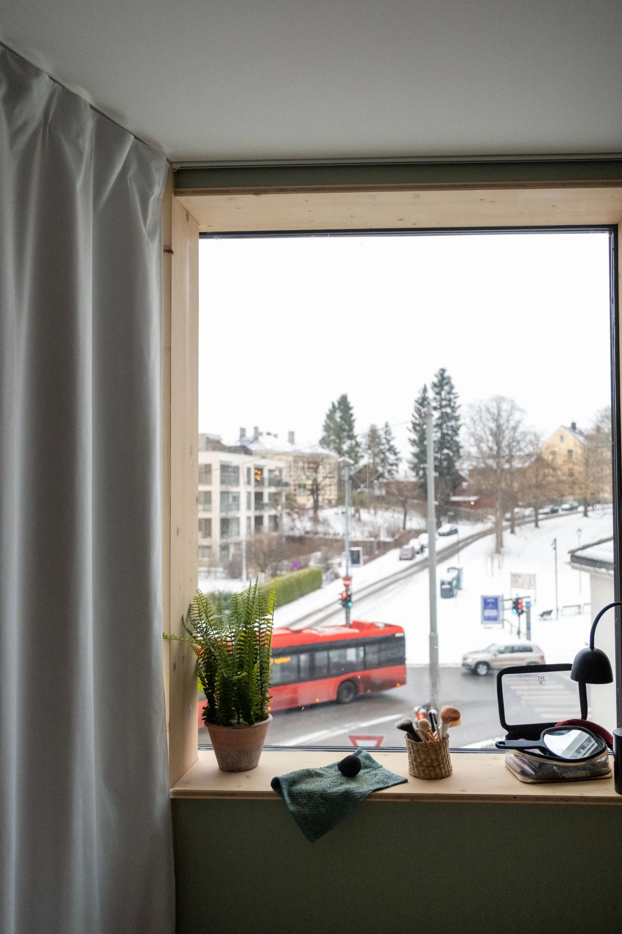 Utsikt fra et soveromsvindu mot en snødekt gate på St. Hanshaugen, der 37-bussen kjører forbi.
