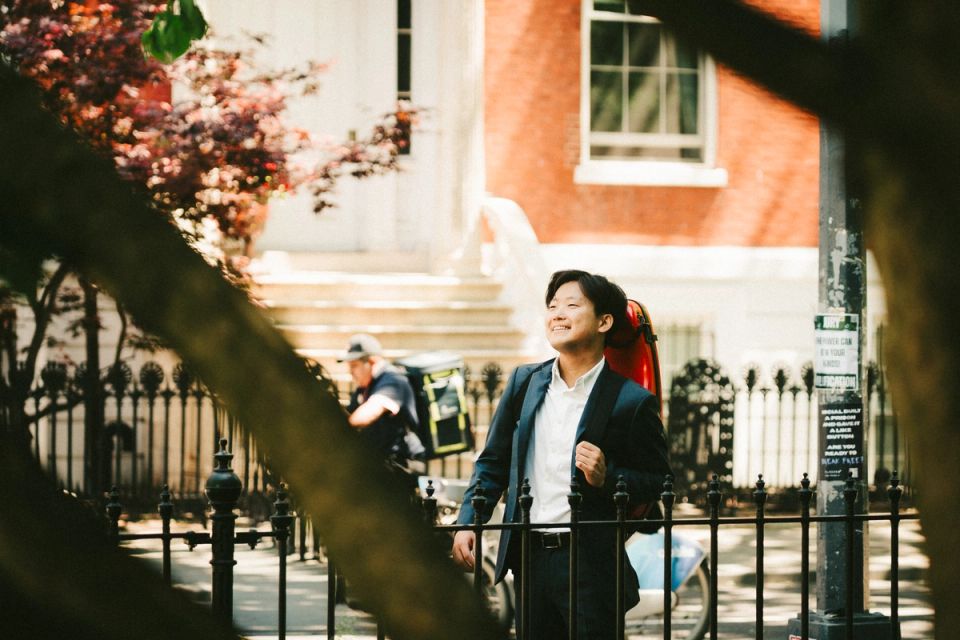 Siwoo Kim smiling by an iron fence, framed by branches